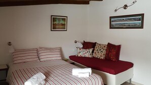 A bedroom with a bed, a sofa, and two framed pictures on the wall. - Cherry House B&B (Polinago)