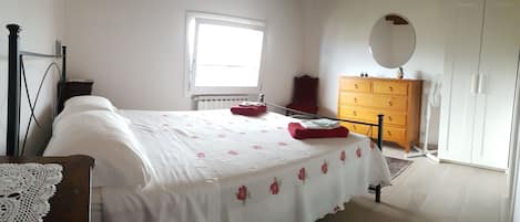 A bedroom with a bed, dresser, and a mirror.