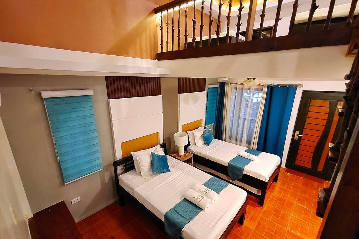 Habitación de hotel con dos camas, una ventana con persianas, una escalera de madera y una puerta de diseño único.