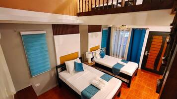 A hotel room with two beds, a window with blinds, a wooden staircase, and a door with a unique design.