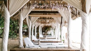 Un espacio de estar al aire libre cubierto, con mesas de madera y toldos blancos.