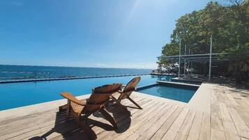 Relax on the deck overlooking the ocean, surrounded by trees and a tranquil atmosphere.
