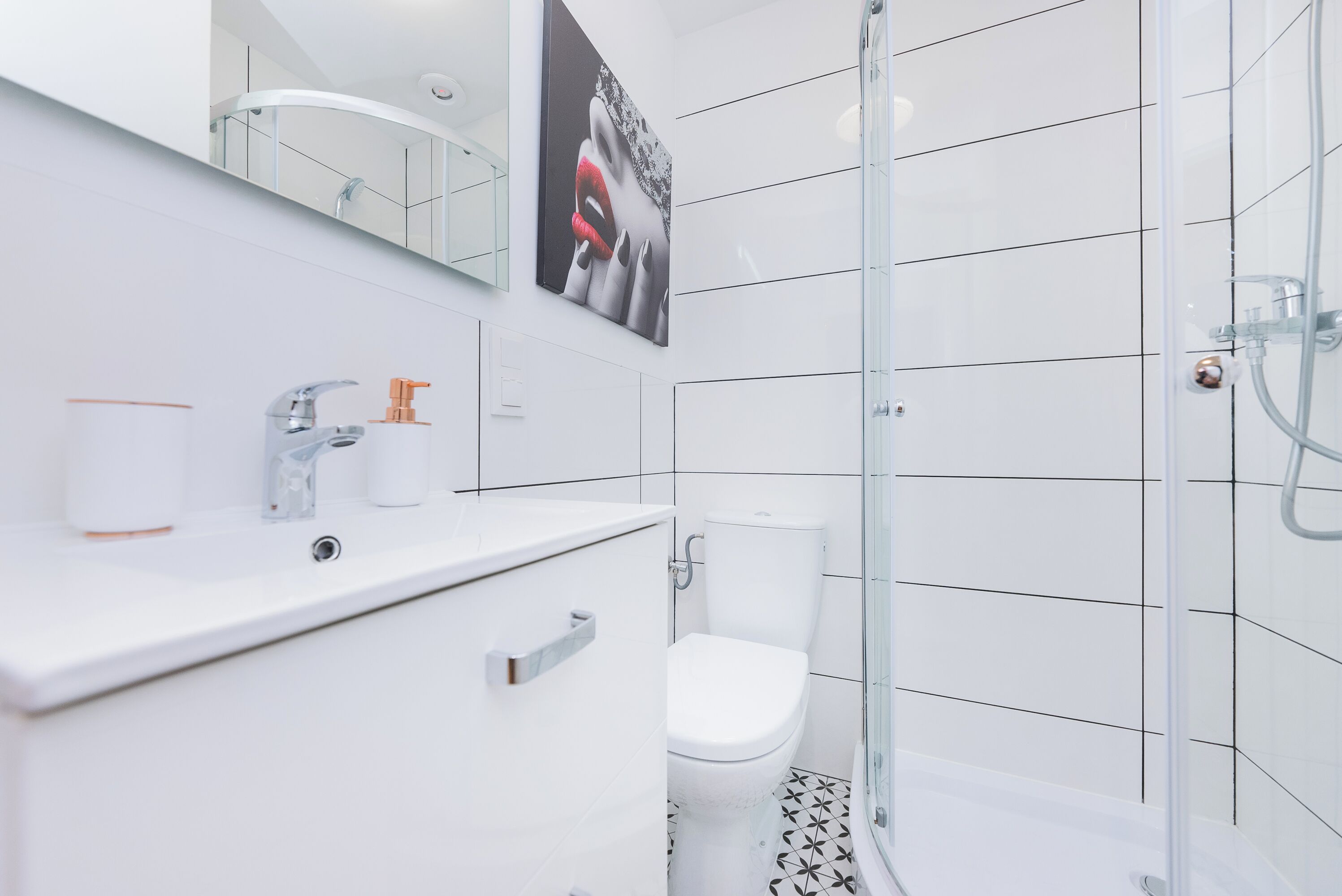 A modern bathroom with a glass shower enclosure, a white sink, and a toilet.