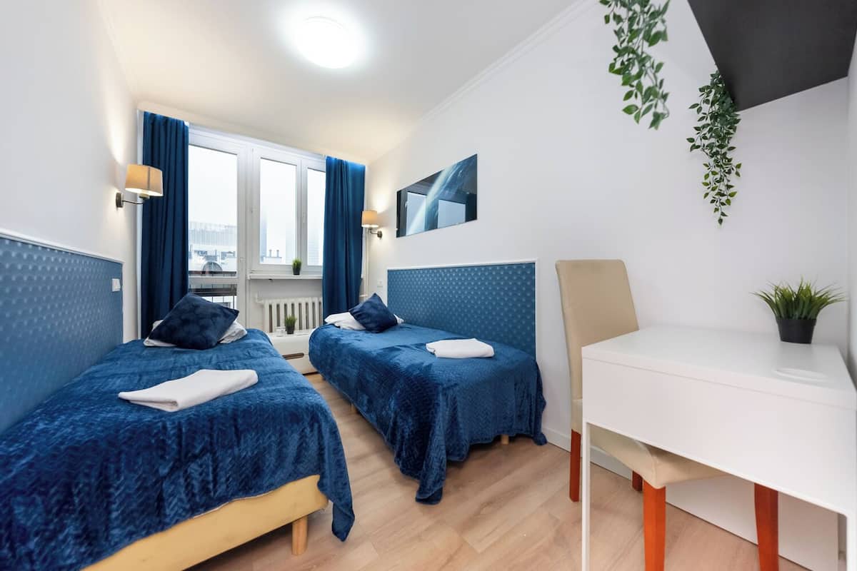 A hotel room with two beds, a desk, and a view of the city.