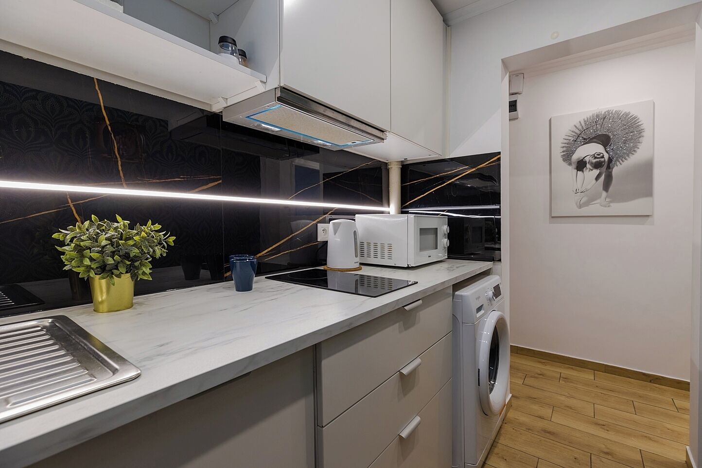 A modern kitchen with a built-in microwave, a coffee maker, and a washing machine.