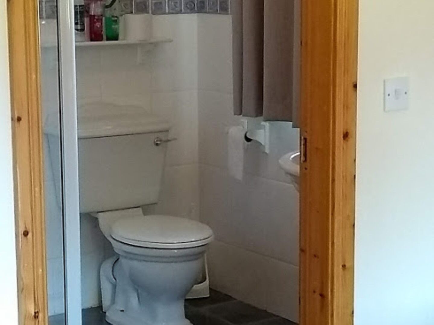 A small bathroom with a toilet, a sink, and a shower area.