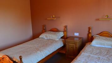 A room with two wooden beds, each with a wooden headboard and a small bedside table.