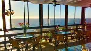 Ein Restaurant am Meer mit Terrassensitzgelegenheiten, großen Fenstern und Blick auf den Ozean.