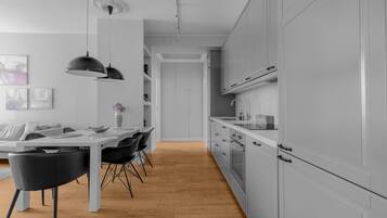 A modern kitchen with white cabinets, a wooden floor, and black chairs.