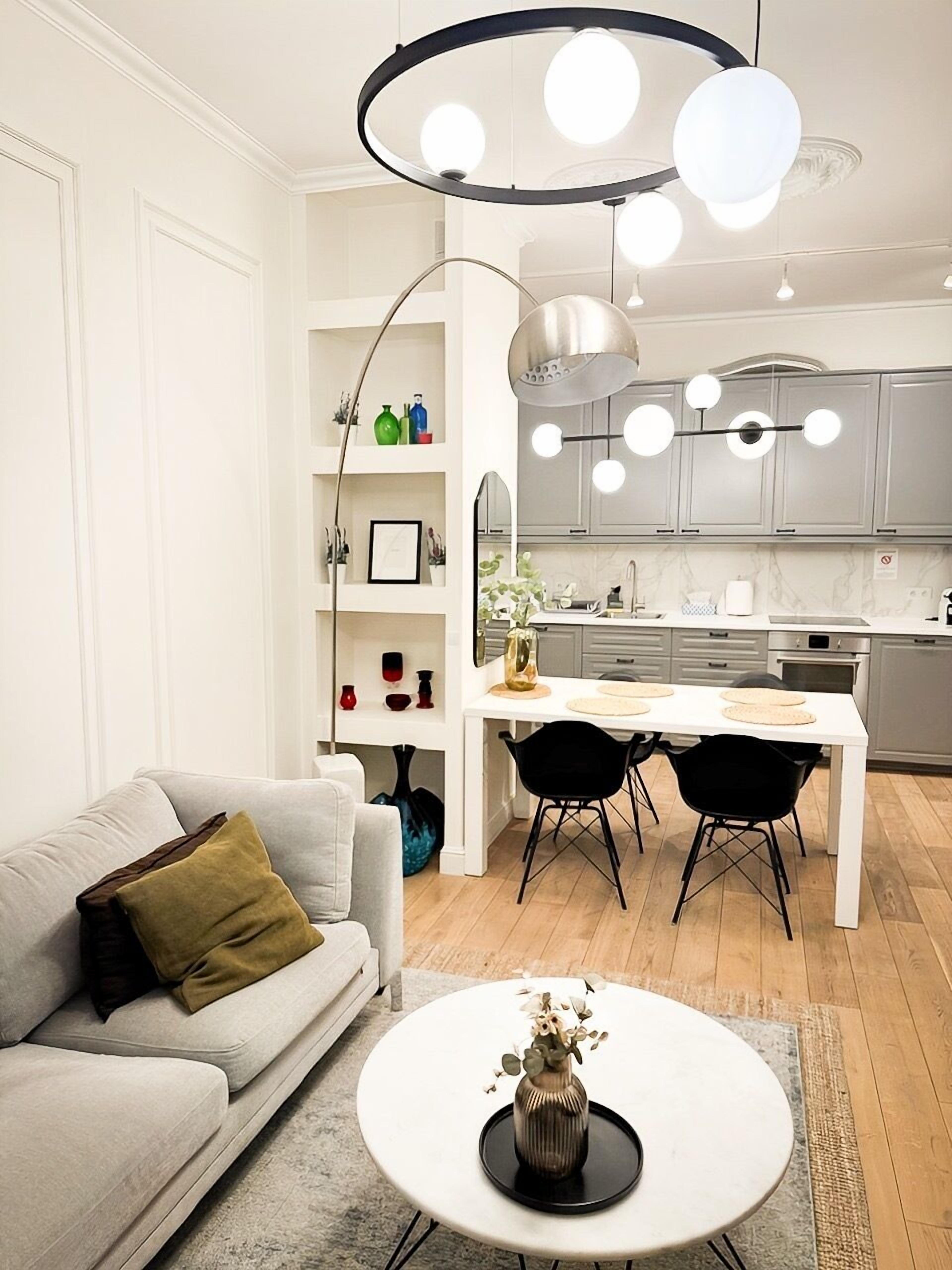 Una sala moderna con un sofá, una mesa de centro y una zona de comedor con una mesa blanca y sillas negras.