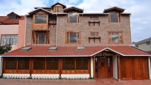 A multi-story house with a stone facade, large windows, and a red-tiled roof. - Hotel Bella Casona (Riobamba)