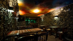 A restaurant with stone walls, wooden tables, and chairs. - Hotel Bella Casona (Riobamba)