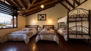 A room with three beds, wooden beams on the ceiling, and a window with a view. - Hotel Bella Casona (Riobamba)