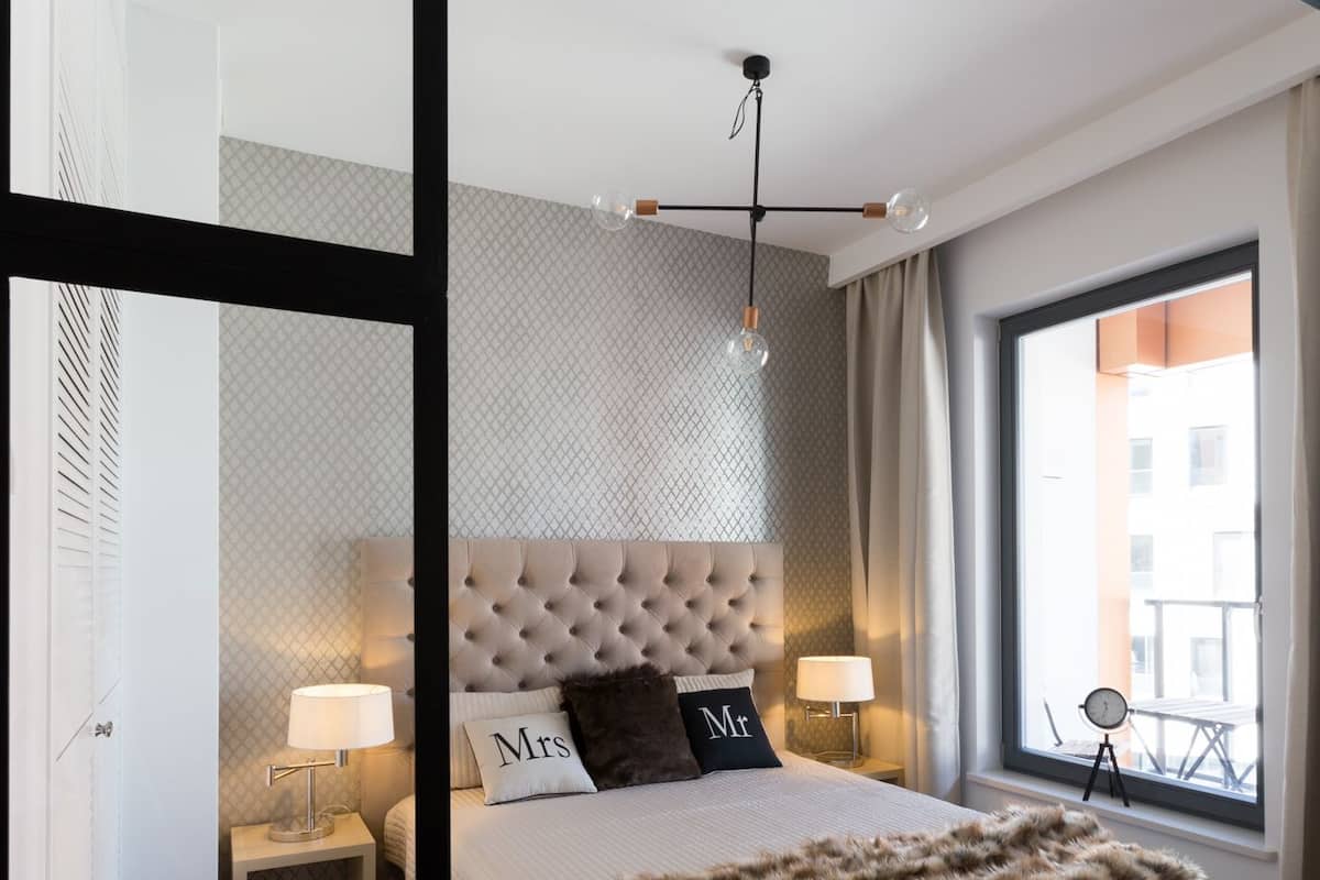 Quarto moderno com cabeceira estofada, uma janela ampla com vista e um cobertor macio sobre a cama.