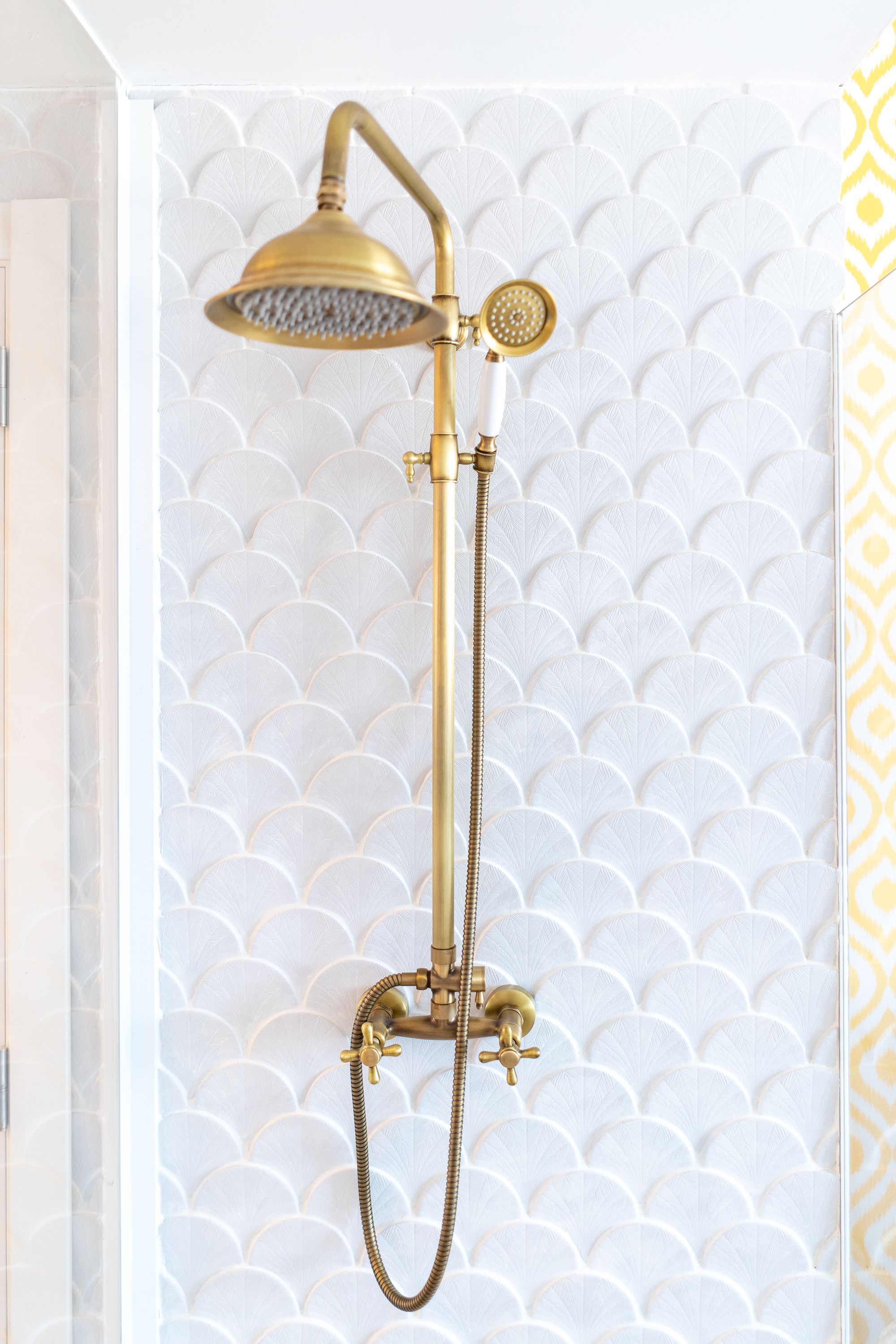 Un pommeau de douche doré, doté d’un flexible et d’un pommeau de douche à main avec une tête circulaire.