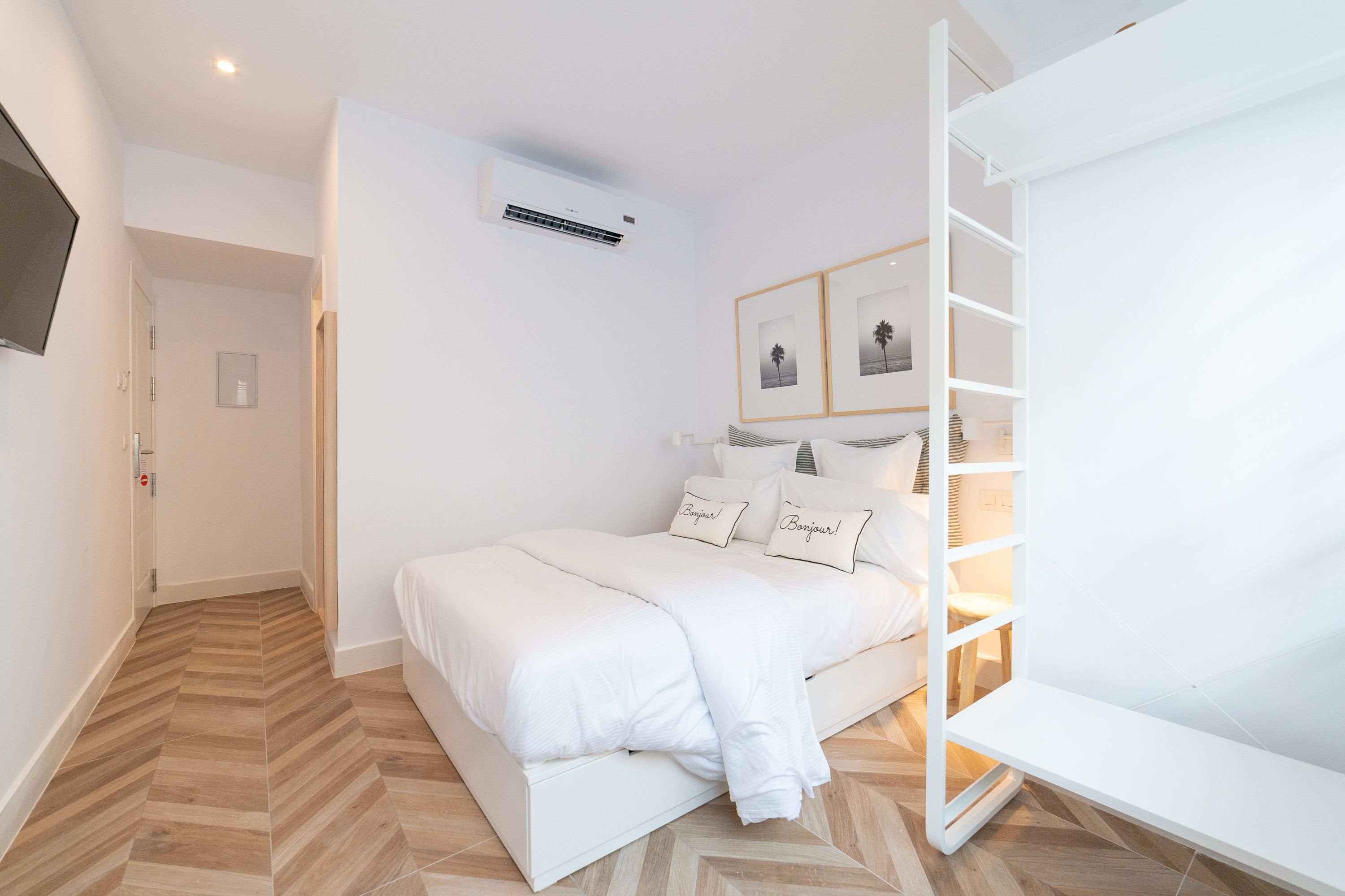 A modern bedroom with a bed, a wardrobe, and a mounted air conditioner.