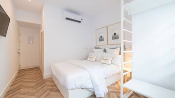 A modern bedroom with a bed, a wardrobe, and a mounted air conditioner.