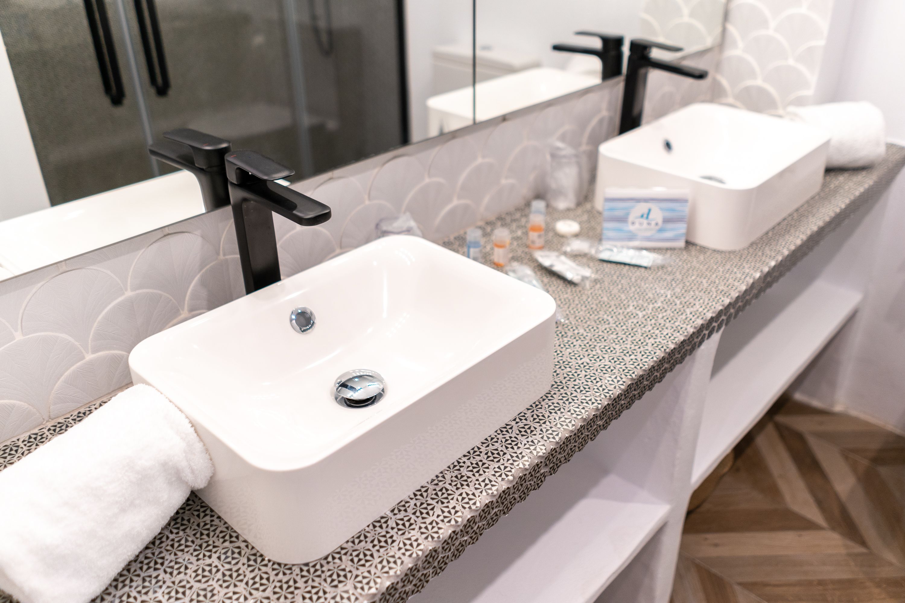 Une salle de bain avec un lavabo blanc, un miroir et une serviette.