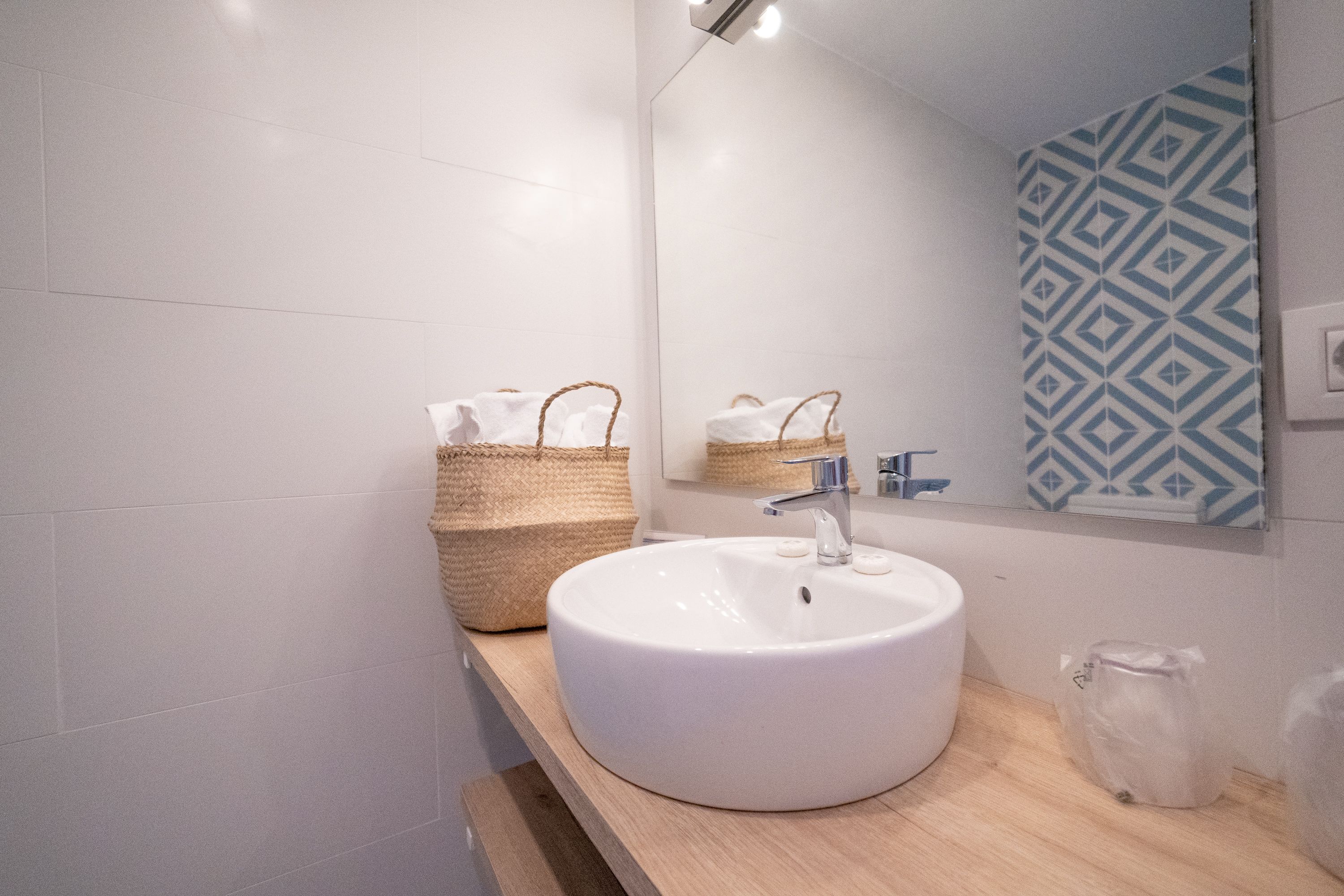 A bathroom with a white sink, a mirror, and a patterned wall.
