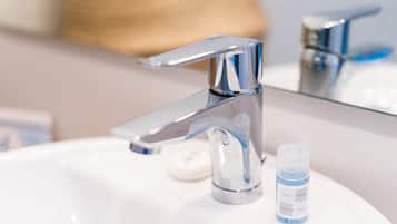 Un lavandino da bagno con un rubinetto cromato e una piccola bottiglia di shampoo.