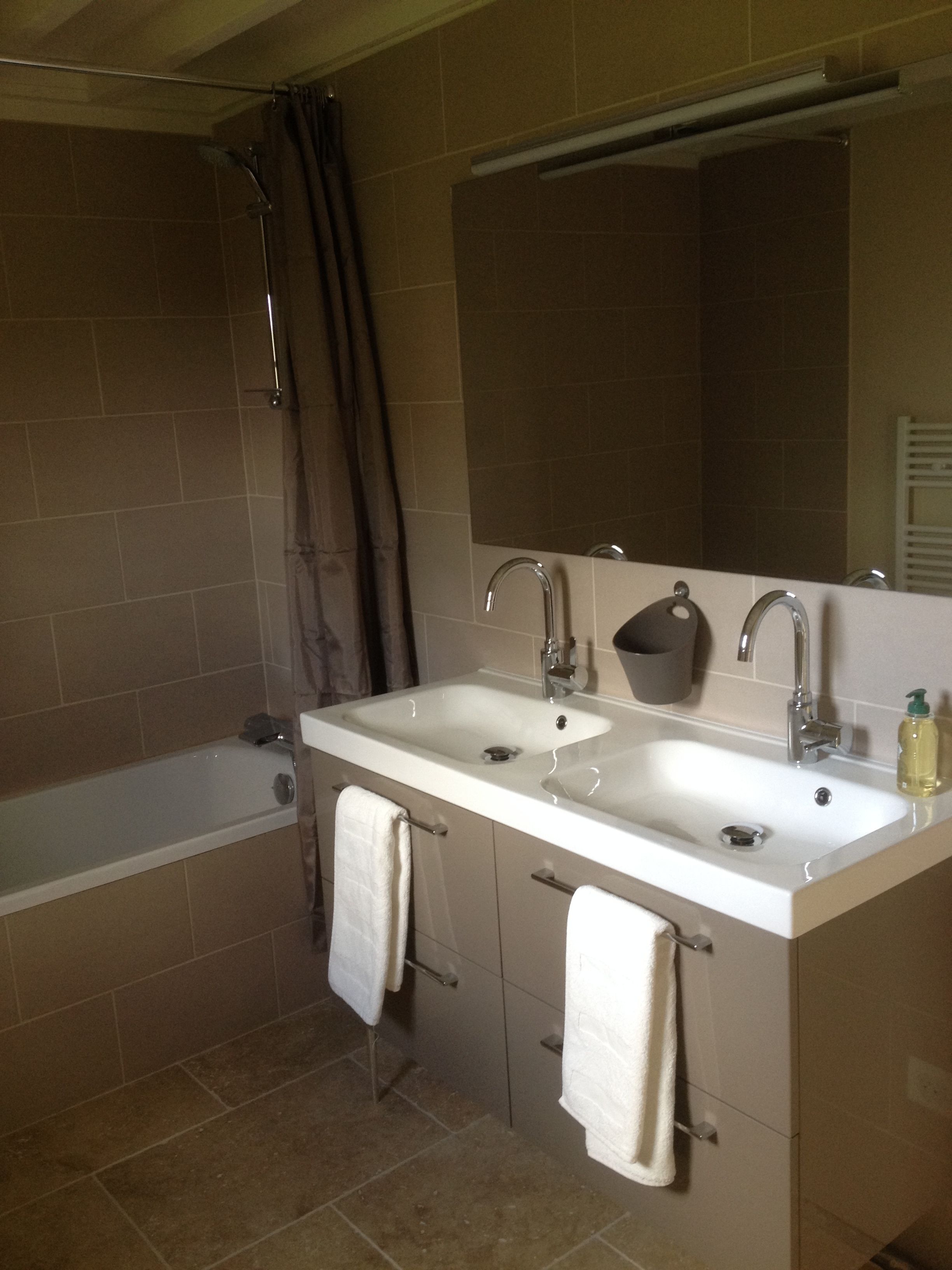 A bathroom with a bathtub, two sinks, a mirror, and a shower curtain.