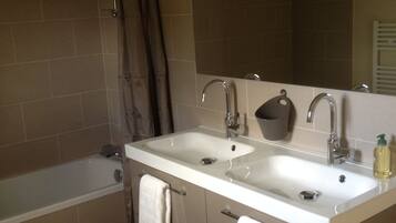 A bathroom with a bathtub, two sinks, a mirror, and a shower curtain.