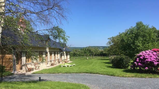 A rustic wooden house with a stone facade, a gravel driveway, and a well-maintained lawn. - L'auberge du Mont (Le Breuil-en-Auge)