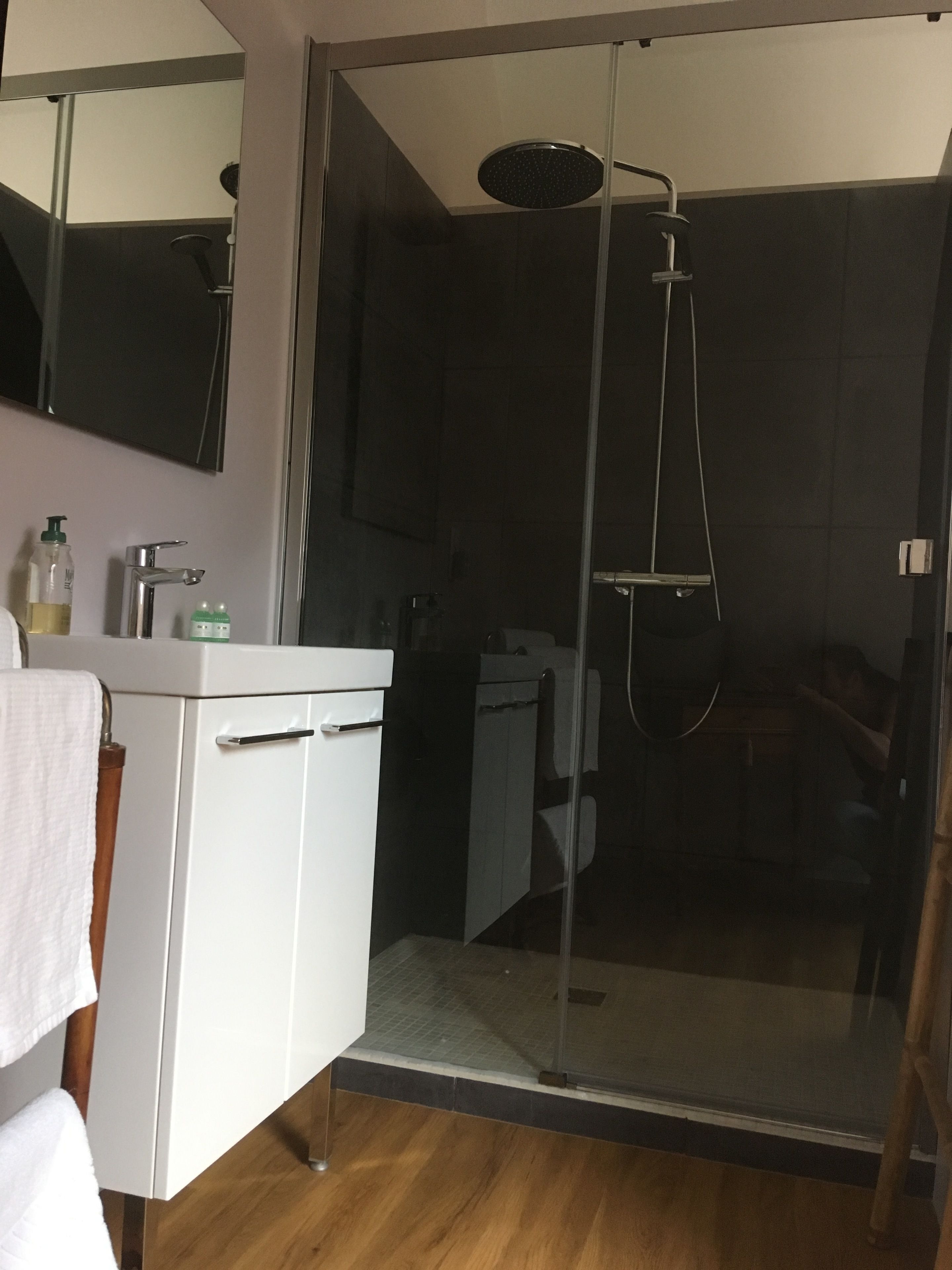 A modern bathroom with a glass shower enclosure, a white vanity, and a mirror above the sink.