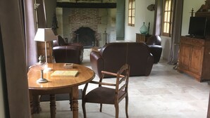 A spacious living room with a fireplace, leather furniture, and a dining area with a table and chairs. - L'auberge du Mont (Le Breuil-en-Auge)
