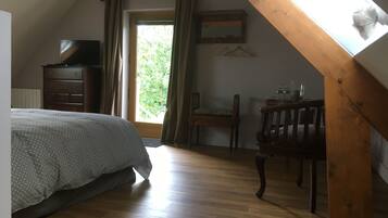 A bedroom with a bed, wooden dresser, chair, and a desk with a mirror.