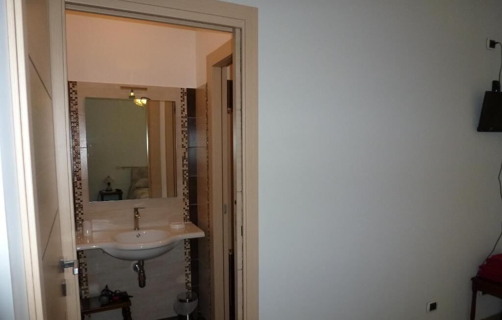 A bathroom with a sink, mirror, and tiled walls.