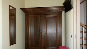 A room with a large wooden wardrobe, a chair, and a television mounted on the wall. - Sogno di Mare (Pula)