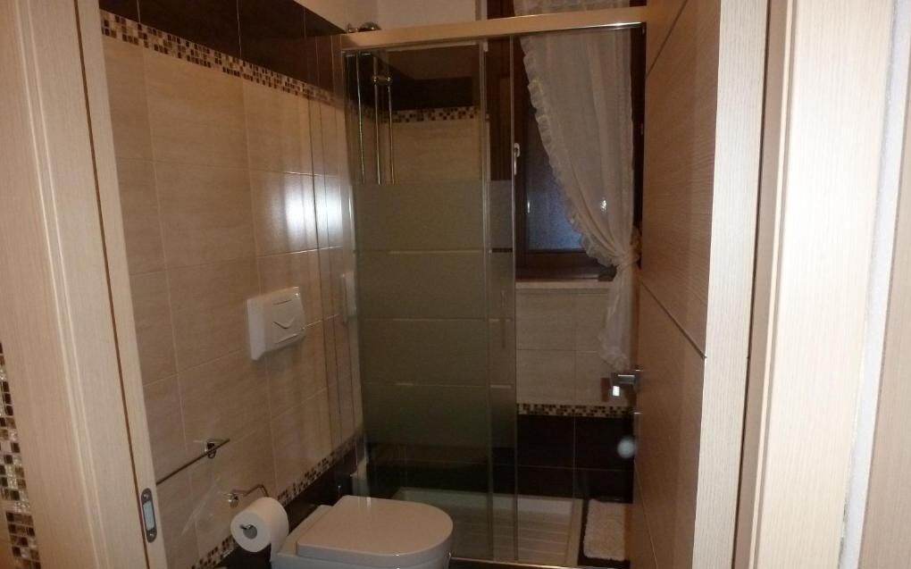 Un baño pequeño con inodoro, cabina de ducha de cristal y paredes de azulejos.