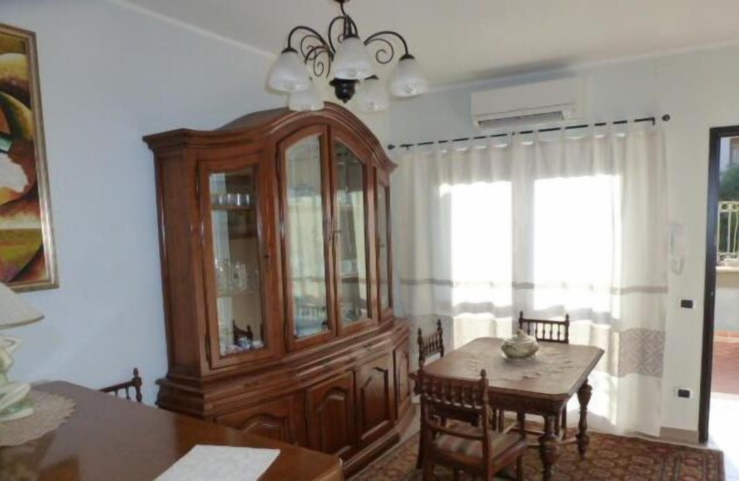 A dining area with a wooden cabinet, a chandelier, and a table with chairs.