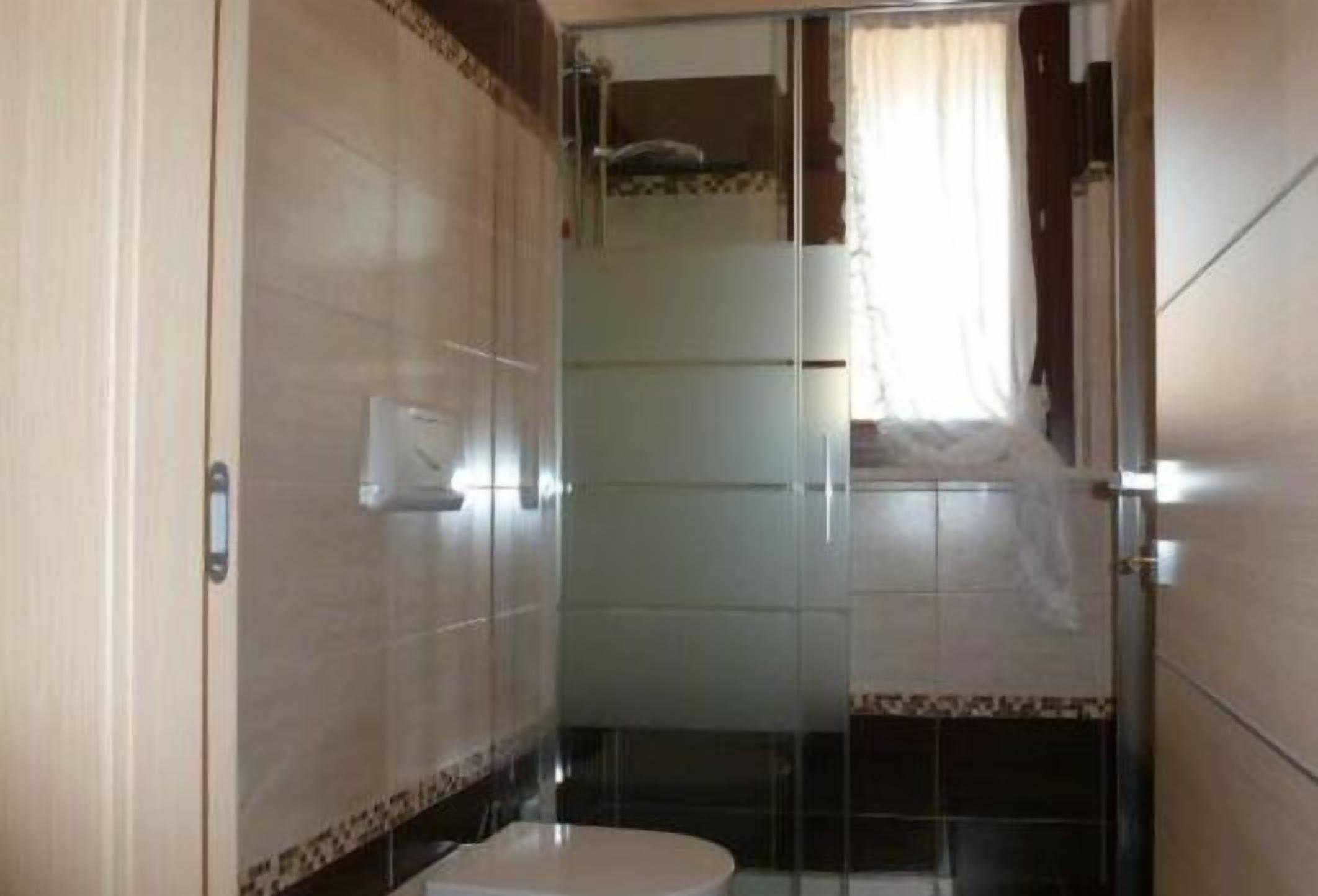 Un baño pequeño con inodoro, cabina de ducha y puerta de vidrio.