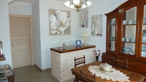 A dining area with a wooden table, chairs, a chandelier, and a cabinet with glass doors. - Sogno di Mare (Pula)