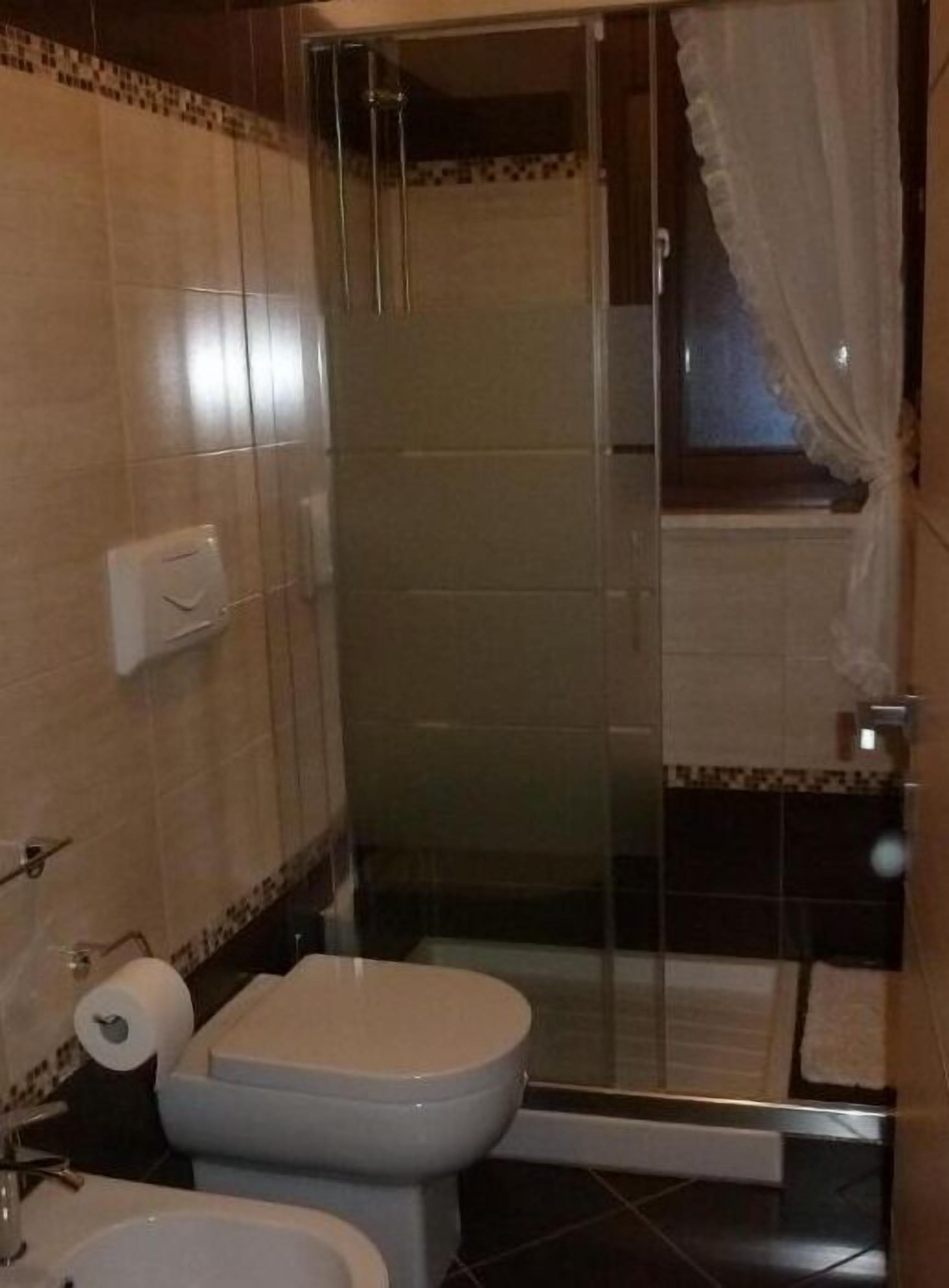 Un baño con inodoro, bidé y cabina de ducha con mampara de vidrio.