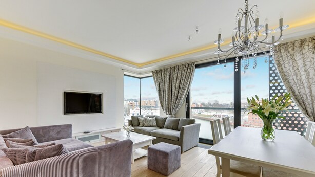 A modern living room with a sofa, ottoman, and dining table. - Navy Group - Old Town Apartments (Gdansk)
