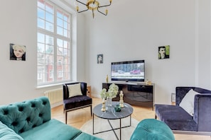 A modern living room with teal sofas, a black coffee table, and artwork on the walls. - Navy Group - Old Town Apartments (Gdansk)