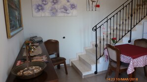 A dining area with a wooden table and chairs, a staircase with a black railing, and artwork on the walls. - Emozioni d'Estate (Pula)
