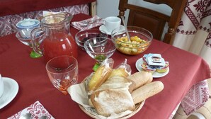 A dining table set with a pitcher of red beverage, bowls of fruit, bread, and condiments. - Emozioni d'Estate (Pula)