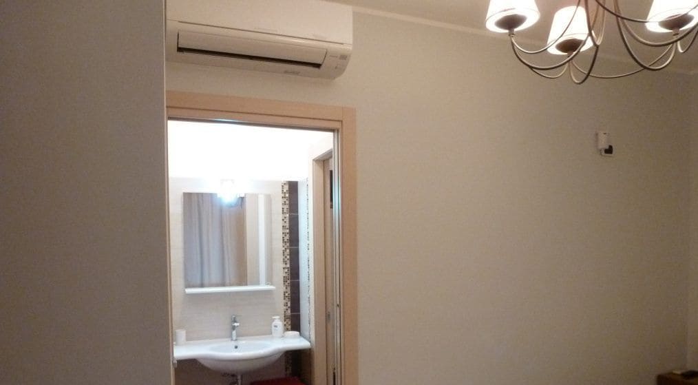 A bathroom with a sink, mirror, and an air conditioning unit.
