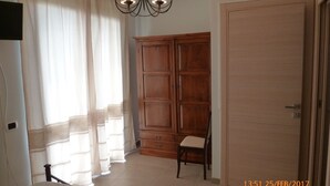 A room with a wooden wardrobe, a chair, and a chandelier. - Emozioni d'Estate (Pula)