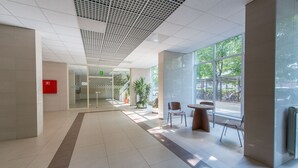A spacious lobby with a tiled floor, a reception desk, and a seating area with chairs and a table.