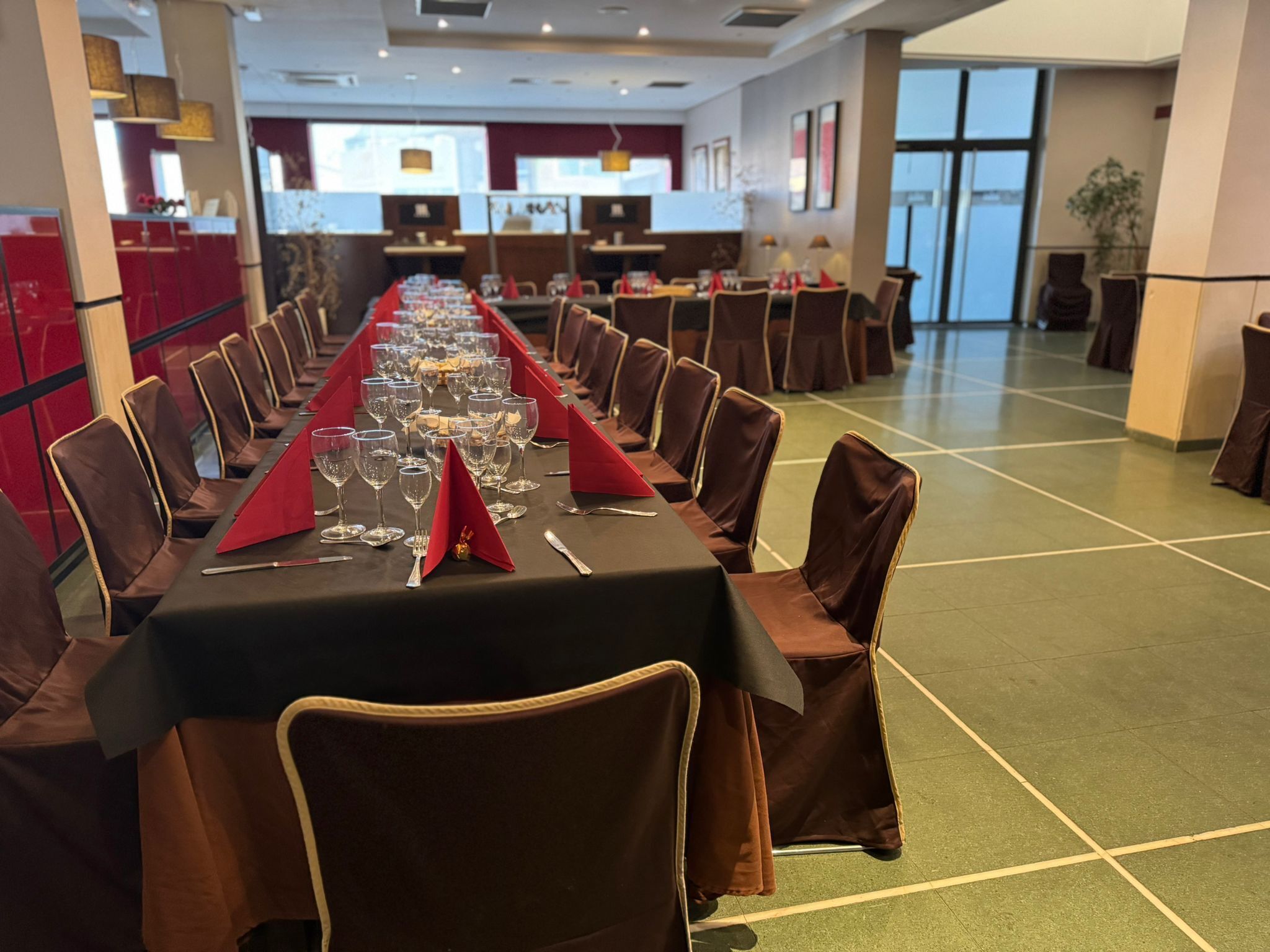 Una larga mesa de banquete dispuesta para un evento formal, con sillas y vajilla.