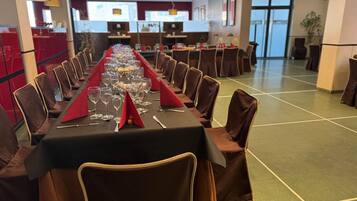 Una larga mesa de banquete dispuesta para un evento formal, con sillas y vajilla.