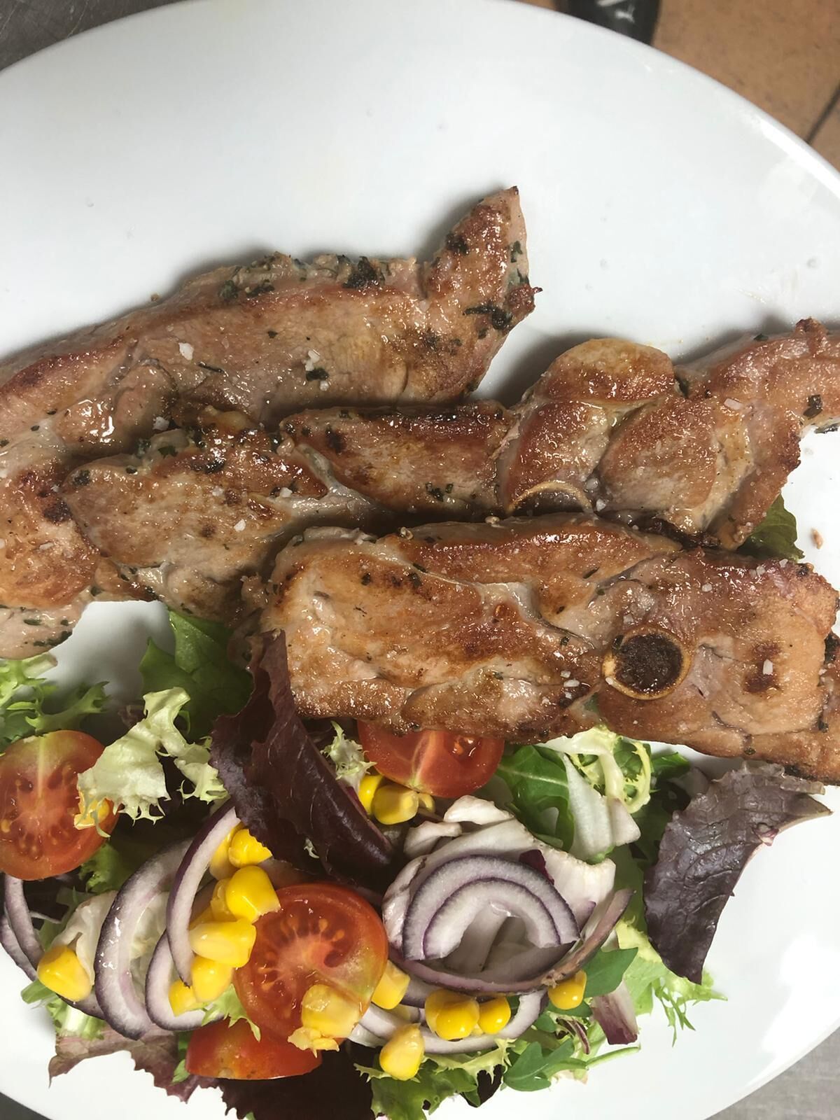 A plate with grilled pork chops and a mixed green salad.