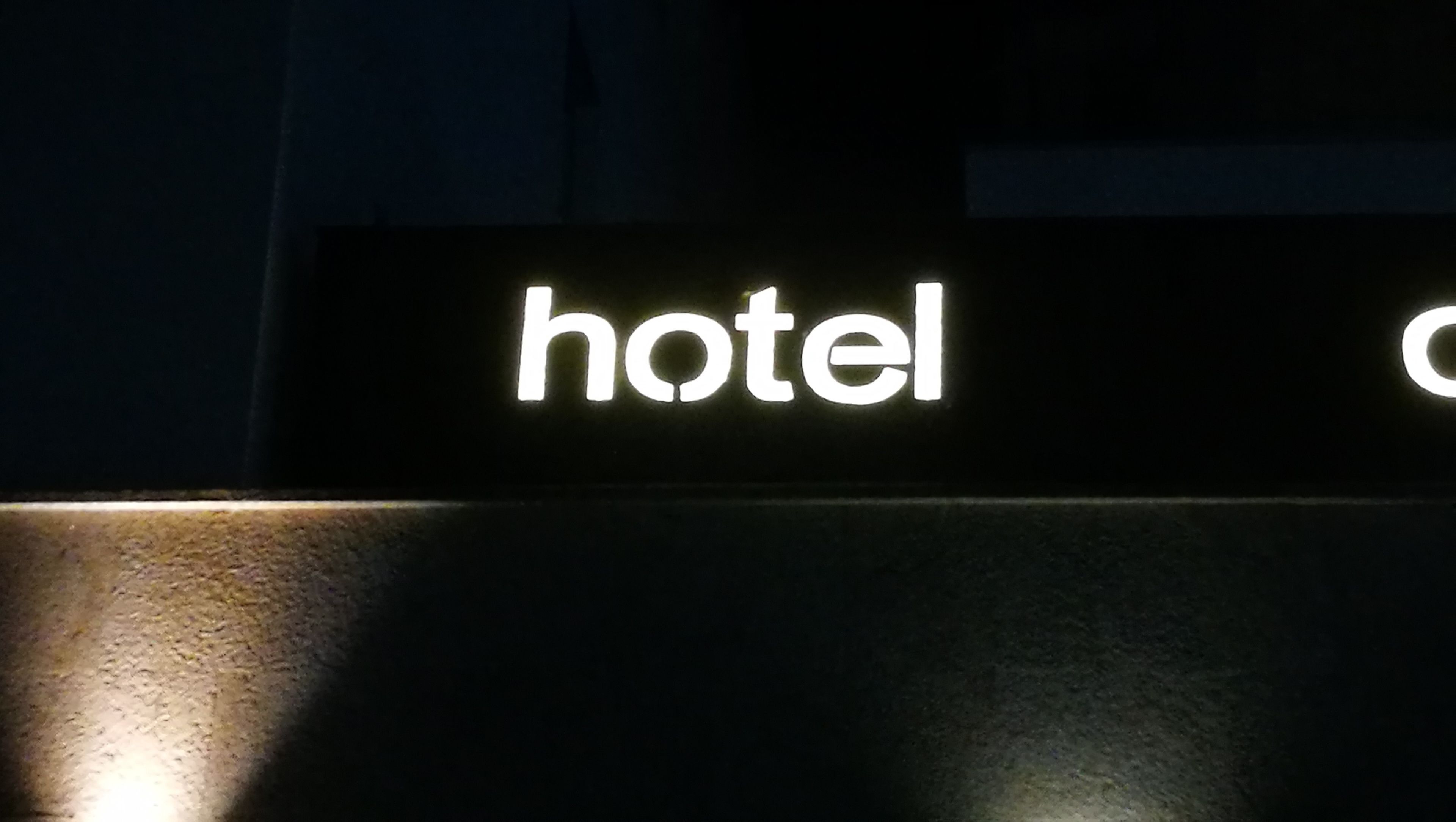 A sign with the word "hotel" illuminated in white against a dark background.