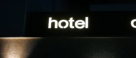 A sign with the word "hotel" illuminated in white against a dark background.