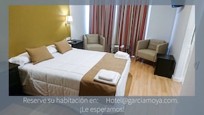 A hotel room with a large bed, two chairs, a small table, and a curtain. - Hotel Moya (Navalmoral de la Mata)